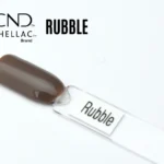 Le visuel montre la capsule du vernis CND™ Shellac Rubble, brun taupe profond et brillant, finition crème homogène.