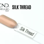 Le visuel montre la capsule du vernis CND™ Shellac Silk Thread, beige rosé irisé au fini soyeux et lumineux.