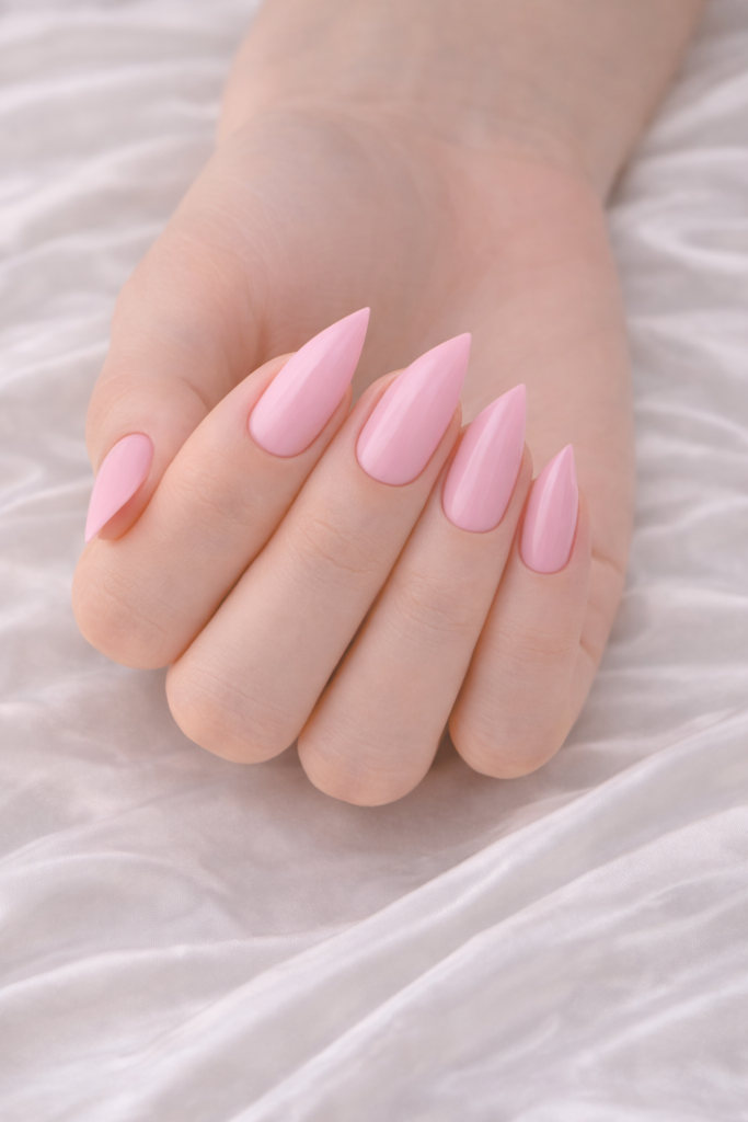 Main avec ongles en forme flèche et vernis rose clair brillant