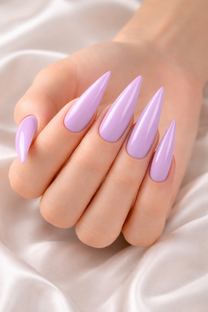 Manucure avec ongles longs en forme stiletto et vernis lilas pastel brillant